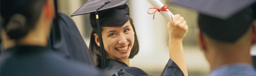 female dressed in cap & gown receiving her diploma